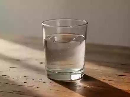 Ein Glas Wasser steht auf einer Holzoberfläche in sanftem Tageslicht. - Foto: über boerse-global.de