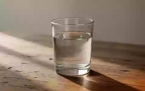 Ein Glas Wasser steht auf einer Holzoberfläche in sanftem Tageslicht. - Foto: über boerse-global.de
