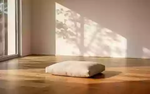 Ein minimalistischer, heller Meditationsraum mit einem einzelnen beigen Sitzkissen auf einem Holzboden und sanftem Tageslicht. - Foto: über boerse-global.de