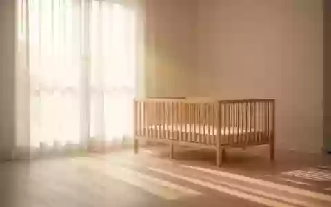 Ein sonnendurchflutetes, minimalistisch eingerichtetes Kinderzimmer mit einem leeren Holzbettchen im weichen Morgenlicht. - Foto: über boerse-global.de
