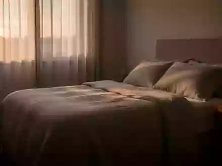Ein ruhig gestaltetes Schlafzimmer im sanften Morgenlicht mit einem ordentlich gemachten Bett und einem Glas Wasser auf dem Nachttisch. - Foto: über boerse-global.de