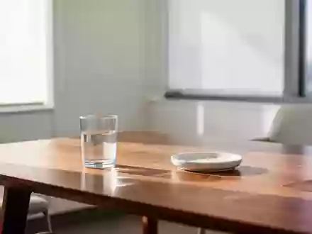 Ein heller, minimalistischer Behandlungsraum mit einem leeren Glas Wasser auf einem Holztisch bei natürlichem Tageslicht. - Foto: über boerse-global.de