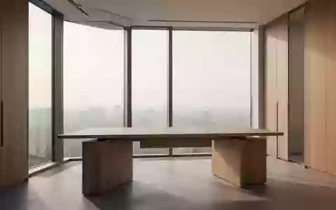 Ein heller, leerer Büroraum mit einem Holztisch vor einem großen Fenster, das natürliches Licht in den Raum wirft. - Foto: über boerse-global.de