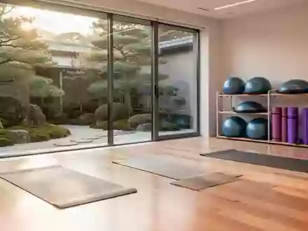Heller, minimalistischer Physiotherapieraum mit Holzboden und Blick in einen grünen Garten, ausgestattet mit Trainingsmatten. - Foto: über boerse-global.de
