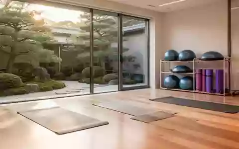 Heller, minimalistischer Physiotherapieraum mit Holzboden und Blick in einen grünen Garten, ausgestattet mit Trainingsmatten. - Foto: über boerse-global.de