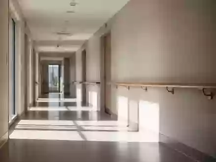 Ein heller, minimalistischer Flur in einer Reha-Klinik mit einem hölzernen Handlauf an einer schlichten Wand. - Foto: über boerse-global.de