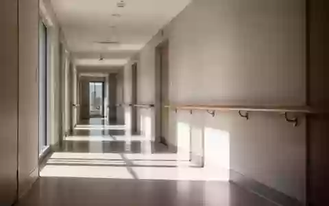 Ein heller, minimalistischer Flur in einer Reha-Klinik mit einem hölzernen Handlauf an einer schlichten Wand. - Foto: über boerse-global.de