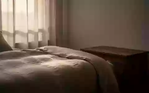 Ein minimalistisch eingerichtetes Schlafzimmer mit weichem Morgenlicht, das auf ein ungemachtes Bett aus Leinen fällt. - Foto: über boerse-global.de