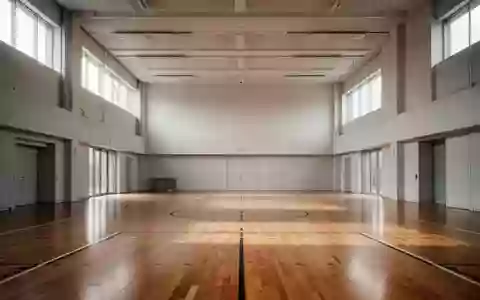 Eine leere, helle Sporthalle mit Parkettboden und großen Fenstern, die Tageslicht in den Raum lassen. - Foto: über boerse-global.de