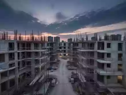 Eine Baustelle mit Rohbauten und Baugerüsten in der Dämmerung, die den Umfang der Wohnungsbauaktivitäten verdeutlicht. - Foto: über boerse-global.de