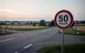 Eine leere Landstraße an einer Kreuzung mit einem Tempolimitschild im Dämmerlicht. - Foto: über boerse-global.de