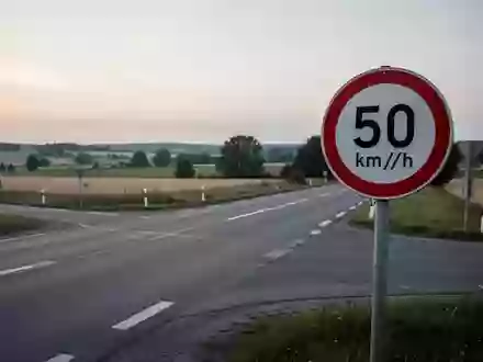 Eine leere Landstraße an einer Kreuzung mit einem Tempolimitschild im Dämmerlicht. - Foto: über boerse-global.de
