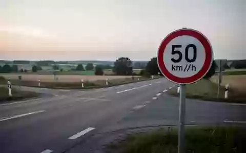 Eine leere Landstraße an einer Kreuzung mit einem Tempolimitschild im Dämmerlicht. - Foto: über boerse-global.de