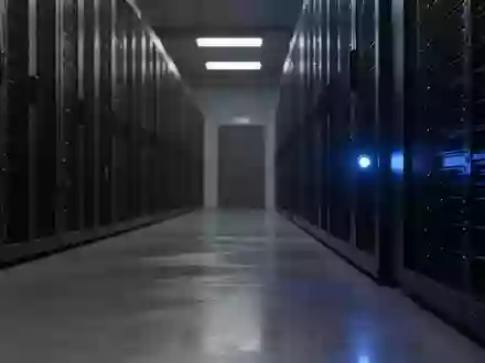 Dunkler, industrieller Serverraum mit einer einsamen blauen Statusleuchte an einem Rack vor einem verschwommenen Hintergrund. - Foto: über boerse-global.de