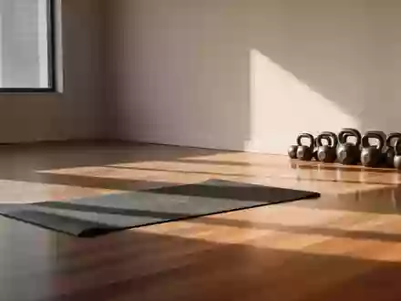 Ein minimalistischer, lichtdurchfluteter Trainingsraum mit einer Yogamatte und Kettlebells auf einem Holzboden. - Foto: über boerse-global.de