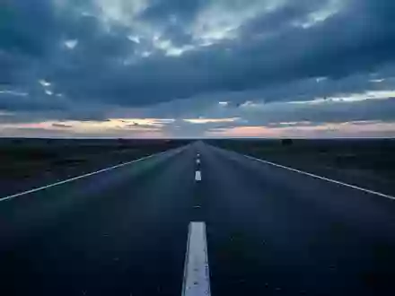 Eine leere, asphaltierte Straße bei Dämmerung unter einem bewölkten Himmel. - Foto: über boerse-global.de