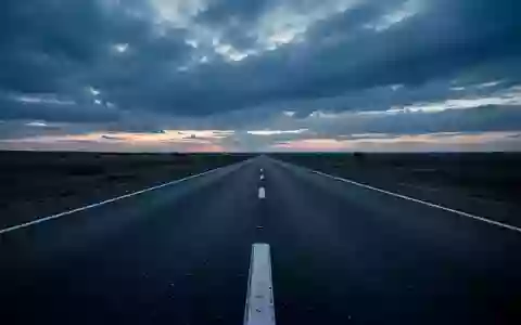 Eine leere, asphaltierte Straße bei Dämmerung unter einem bewölkten Himmel. - Foto: über boerse-global.de