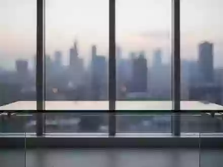 Ein minimalistischer, leerer Arbeitsplatz an einem Fenster mit Blick auf eine verschwommene Stadt bei DĂ€mmerung. - Foto: ĂŒber boerse-global.de