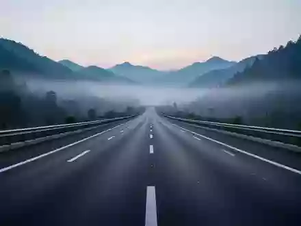 Eine weitläufige, leere Autobahn in einer nebligen Berglandschaft bei Dämmerung, die den Fokus auf die Infrastruktur legt. - Foto: über boerse-global.de
