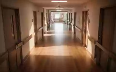 Ein leerer, sonnendurchfluteter Flur in einer modernen Pflegeeinrichtung mit poliertem Holzboden. - Foto: über boerse-global.de