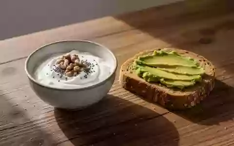 Ein ausgewogenes Frühstück mit Joghurt, Nüssen und Vollkornbrot auf einem Holztisch bei natürlichem Morgenlicht. - Foto: über boerse-global.de