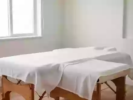 Ein minimalistischer Behandlungsraum mit einer leeren Massageliege und weißem Laken in einer ruhigen, professionellen Umgebung. - Foto: über boerse-global.de