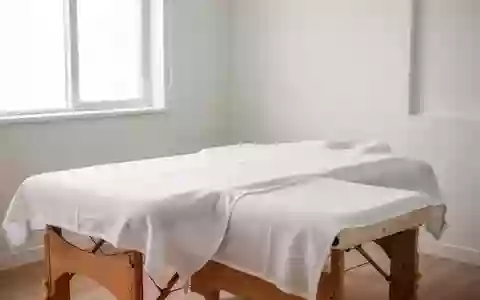 Ein minimalistischer Behandlungsraum mit einer leeren Massageliege und weißem Laken in einer ruhigen, professionellen Umgebung. - Foto: über boerse-global.de
