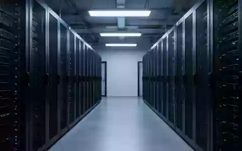 Reihen von schwarzen Server-Racks in einem minimalistischen, blau beleuchteten Rechenzentrum. - Foto: über boerse-global.de