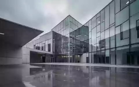 Ein modernes, minimalistisches Regierungsgebäude in Brüssel mit scharfen Glaswinkeln und polierten Betonoberflächen unter grauem Himmel. - Foto: über boerse-global.de