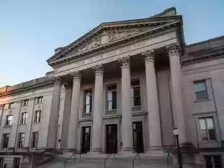 Die Fassade eines historischen Gerichtsgebäudes mit großen Steinsäulen vor einem klaren Himmel. - Foto: über boerse-global.de