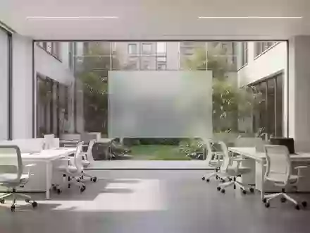 Ein minimalistischer, lichtdurchfluteter moderner Arbeitsbereich mit hellen Möbeln und Blick auf einen grünen Innenhof. - Foto: über boerse-global.de