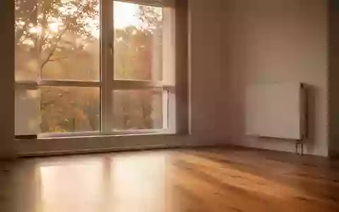 Ein helles, modern eingerichtetes Wohnzimmer im Herbst mit einfallendem Sonnenlicht und einem schlichten Heizkörper an der Wand. - Foto: über boerse-global.de