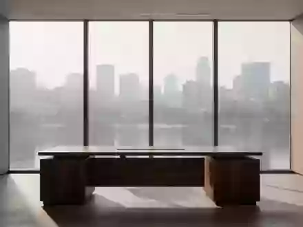 Ein minimalistisch eingerichtetes, leeres Büro mit einem dunklen Holztisch vor einer großen Fensterfront. - Foto: über boerse-global.de