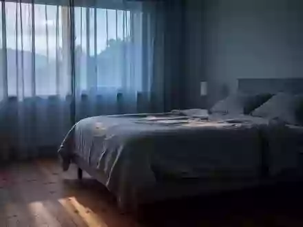 Ein ruhiges Schlafzimmer im sanften Licht der frühen Morgendämmerung mit einem unbenutzten, ordentlich gemachten Bett. - Foto: über boerse-global.de