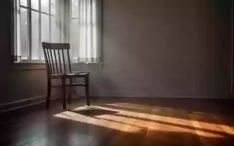 Ein minimalistischer, von Sonnenlicht durchfluteter Raum mit einem leeren Holzstuhl und weichen Schatten auf einem Holzboden. - Foto: über boerse-global.de