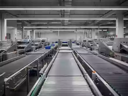 Leeres, modernes Sortierzentrum eines Postdienstleisters mit automatisierten Förderbändern in einer Industriehalle. - Foto: über boerse-global.de
