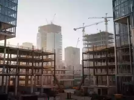 Eine moderne Baustelle mit Stahl- und Glaskonstruktionen in einem städtischen Entwicklungsgebiet bei Tageslicht. - Foto: über boerse-global.de