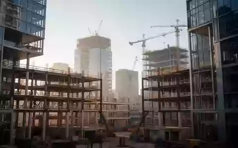 Eine moderne Baustelle mit Stahl- und Glaskonstruktionen in einem städtischen Entwicklungsgebiet bei Tageslicht. - Foto: über boerse-global.de