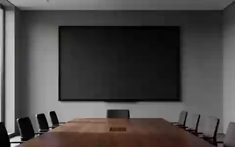 Ein minimalistischer Konferenzraum mit einer leeren, dunklen Projektionsfläche vor einer neutralen Wand. - Foto: über boerse-global.de
