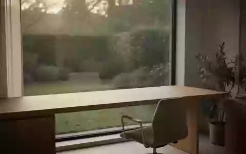 Ein minimalistisch eingerichteter, heller Arbeitsplatz mit Schreibtisch und Stuhl vor einem Fenster mit Blick ins Grüne. - Foto: über boerse-global.de