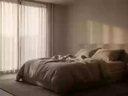 Ein minimalistisch eingerichtetes Schlafzimmer mit sanftem Tageslicht, das durch Vorhänge fällt und eine ruhige Atmosphäre schafft. - Foto: über boerse-global.de