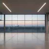 Ein moderner, leerer Flughafen-Abflugbereich mit großen Glasfronten und Blick auf das Rollfeld bei Dämmerung. - Foto: über boerse-global.de