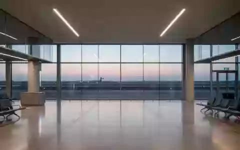 Ein moderner, leerer Flughafen-Abflugbereich mit großen Glasfronten und Blick auf das Rollfeld bei Dämmerung. - Foto: über boerse-global.de