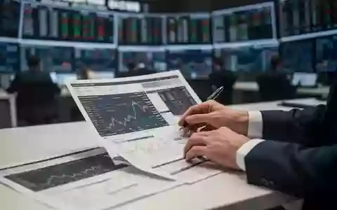 Nahaufnahme der Hände eines Geschäftsmannes an einem Schreibtisch vor einem unscharfen Hintergrund eines Börsenparketts. - Foto: über boerse-global.de