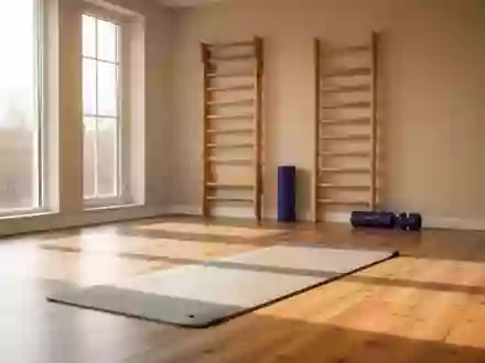 Ein heller, minimalistischer Physiotherapieraum mit einer leeren Gymnastikmatte und einer Sprossenwand im Hintergrund. - Foto: über boerse-global.de