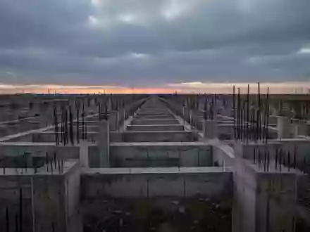 Eine weite, verlassene Baustelle mit Betonfundamenten unter einem bewölkten Himmel, die wirtschaftliche Unsicherheit symbolisiert. - Foto: über boerse-global.de