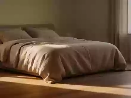 Ein sonnendurchflutetes, ruhiges Schlafzimmer am Nachmittag mit einem ordentlich gemachten Bett und minimalistischer Einrichtung. - Foto: über boerse-global.de