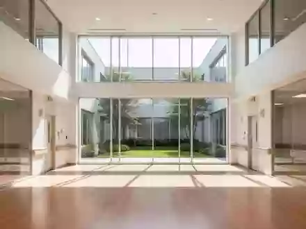 Ein minimalistisches, helles Krankenhaus-Atrium mit Holzboden und Blick in einen begrünten Innenhof. - Foto: über boerse-global.de