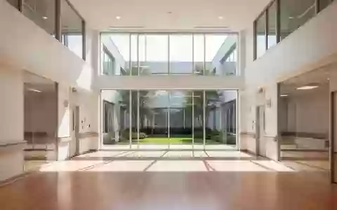 Ein minimalistisches, helles Krankenhaus-Atrium mit Holzboden und Blick in einen begrünten Innenhof. - Foto: über boerse-global.de