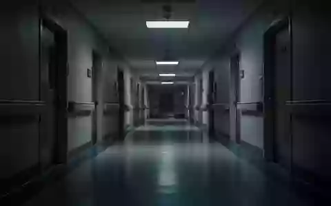 Ein leerer, schwach beleuchteter Krankenhausflur bei Nacht mit langen Schatten und glänzenden Bodenbelägen. - Foto: über boerse-global.de